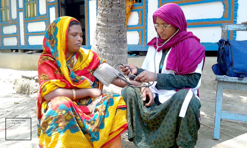 A Health Volunteer is checking blood pressure of a woman during Home-Visit